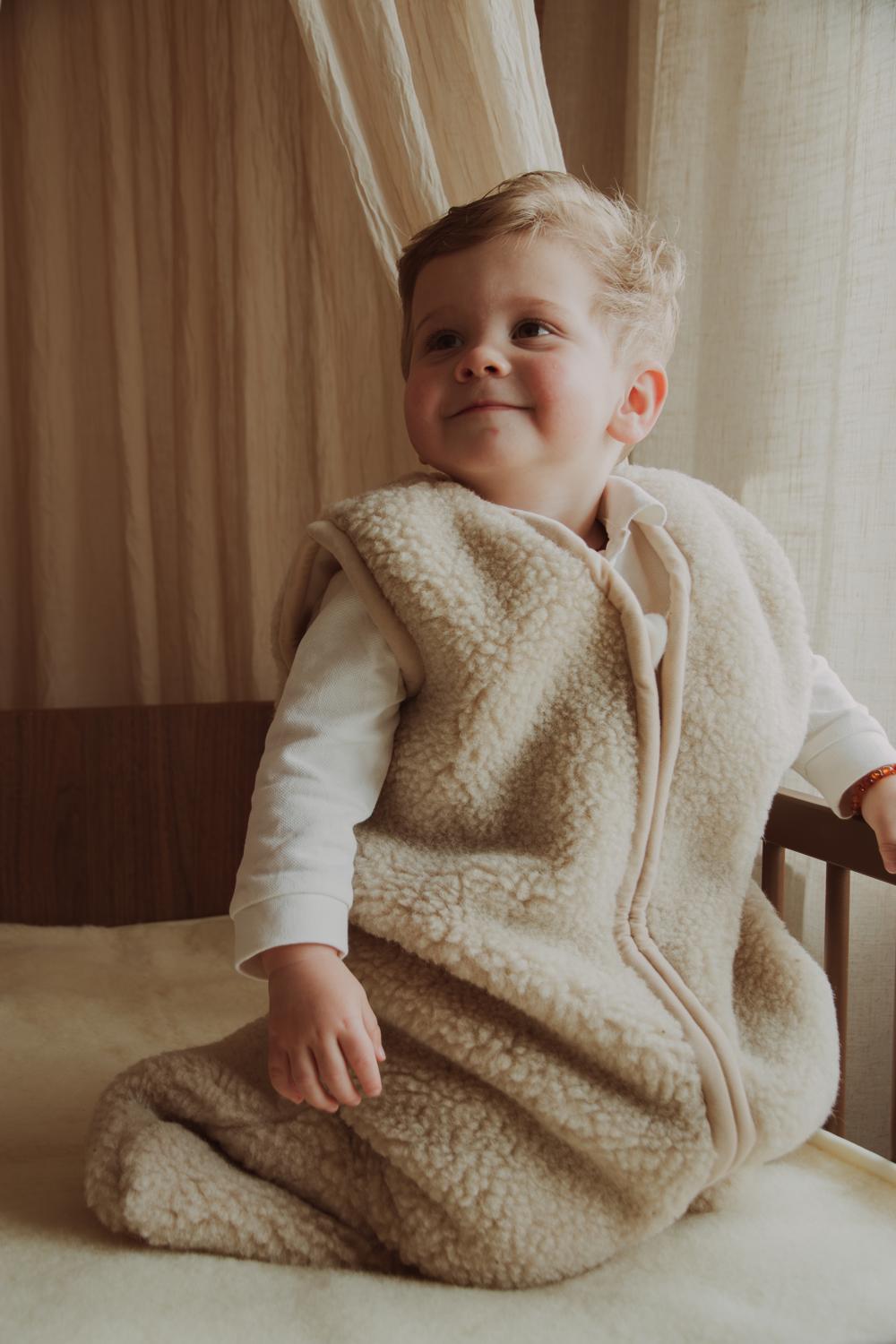 Jongetje in een wollen slaapzak van Schaapmaatje in een houten bed