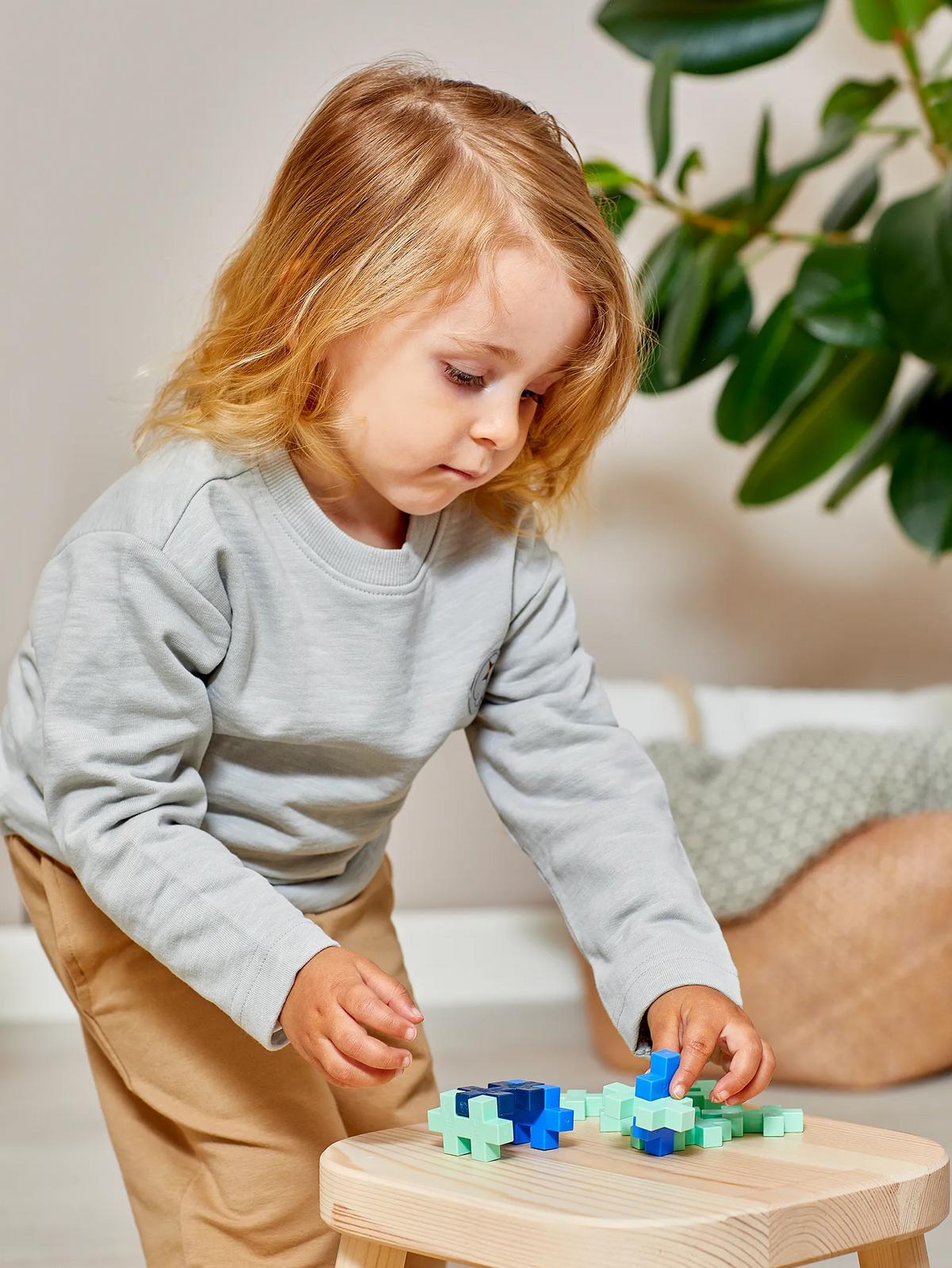 Kind bouwt met Plus-Plus BIG aan een houten tafeltje in een warme woonkamer
